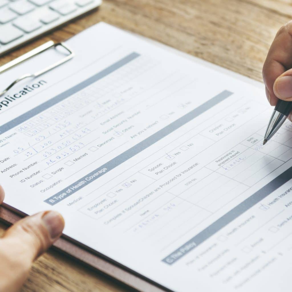 Man's hands with pen writing on clipboard