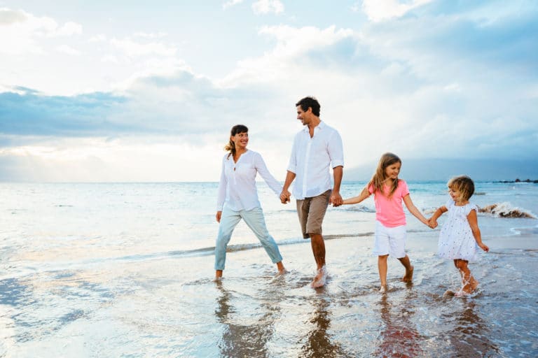 Family of four walking in ocean surf